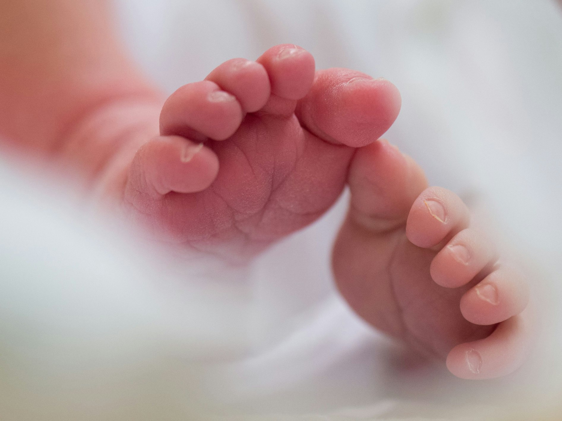 Ein Säugling liegt in einem Bett auf der Wochenstation in einem Universitätsklinikum.