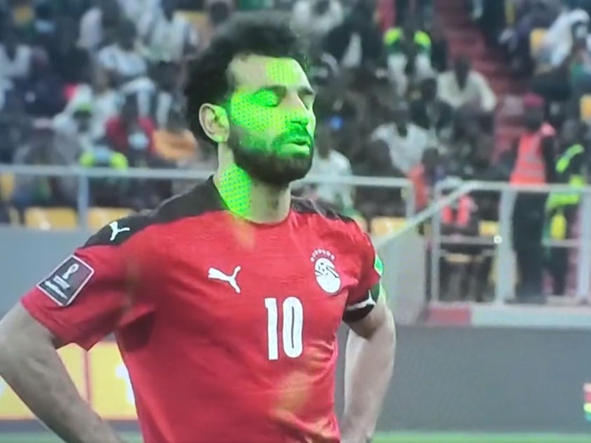 Mehrere Laserpointer sind auf das Gesicht von Mohamed Salah gerichtet.