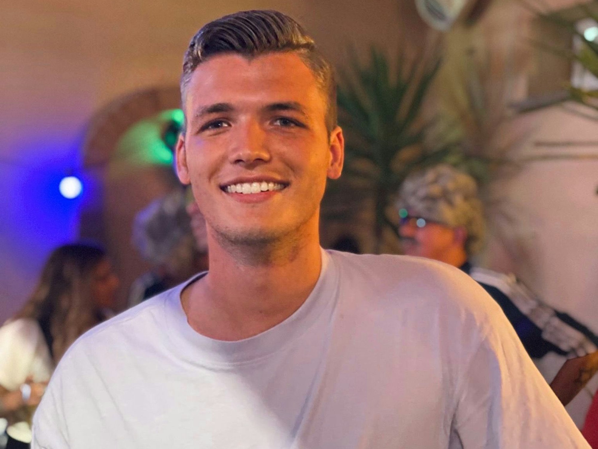 Sänger Julian Sommer lächelt in die Kamera und hat ein Mikrofon in der Hand.