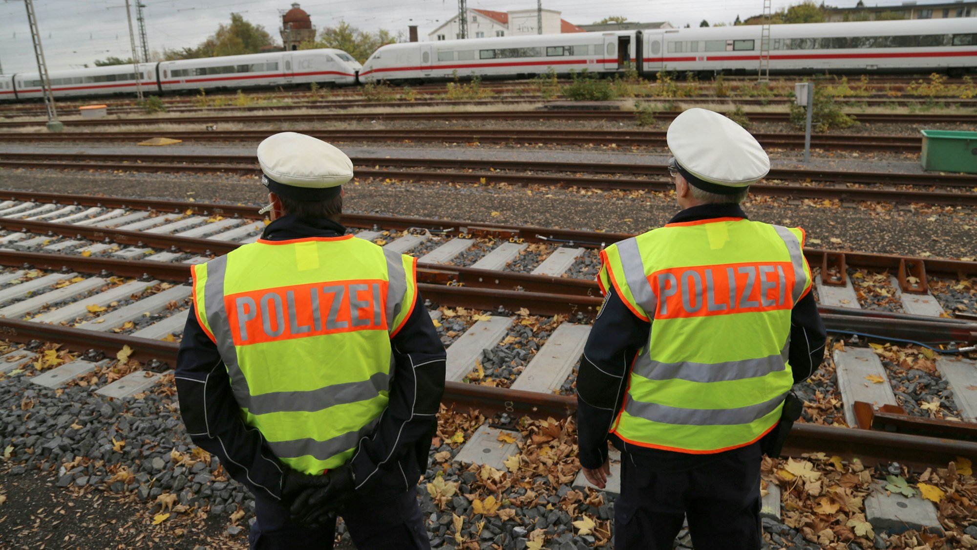 Polizisten stehen auf einem Güterbahnhof neben einem ICE.
