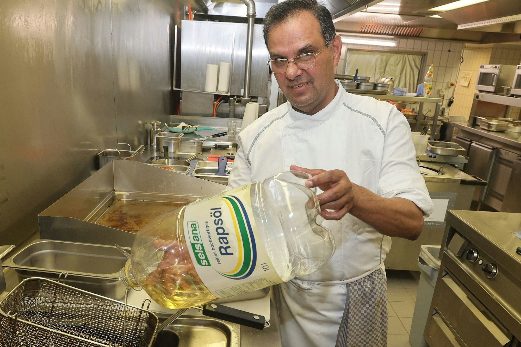 Im „Gaffel am Dom“ gibt es ab dem 1. April keine Pommes mehr. Koch Abdul Schneider füllt das letzte Öl in die Fritteuse – in diesem Fall Rapsöl.