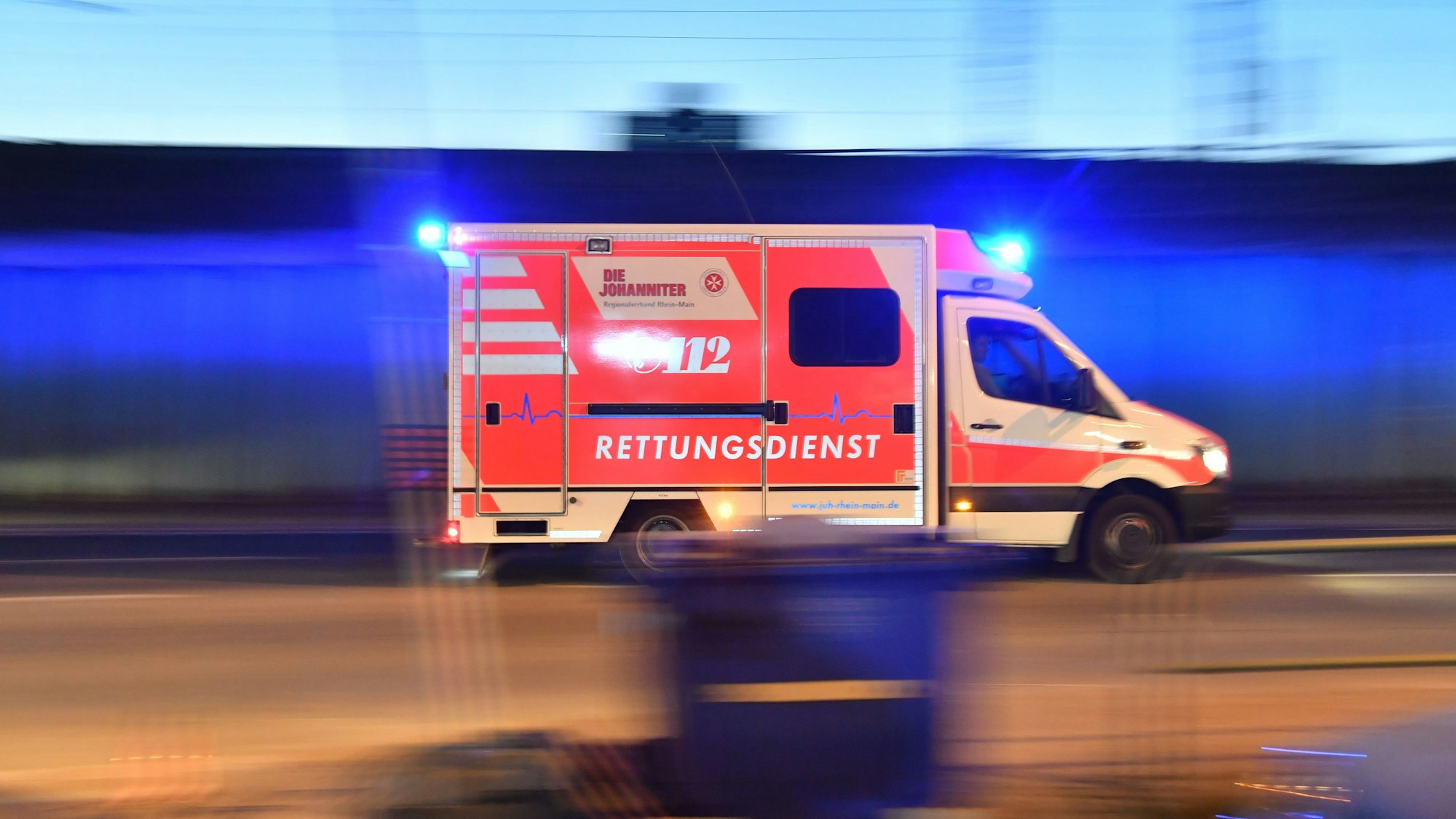Ein Rettungswagen ist mit eingeschaltetem Blauchlicht im Einsatz.