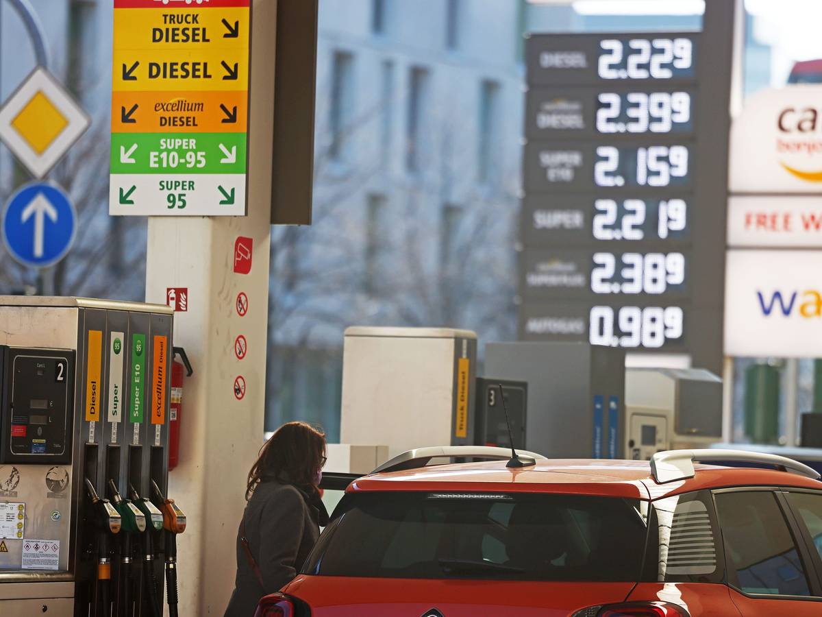Frau steht mit Auto an einer Tankstelle.