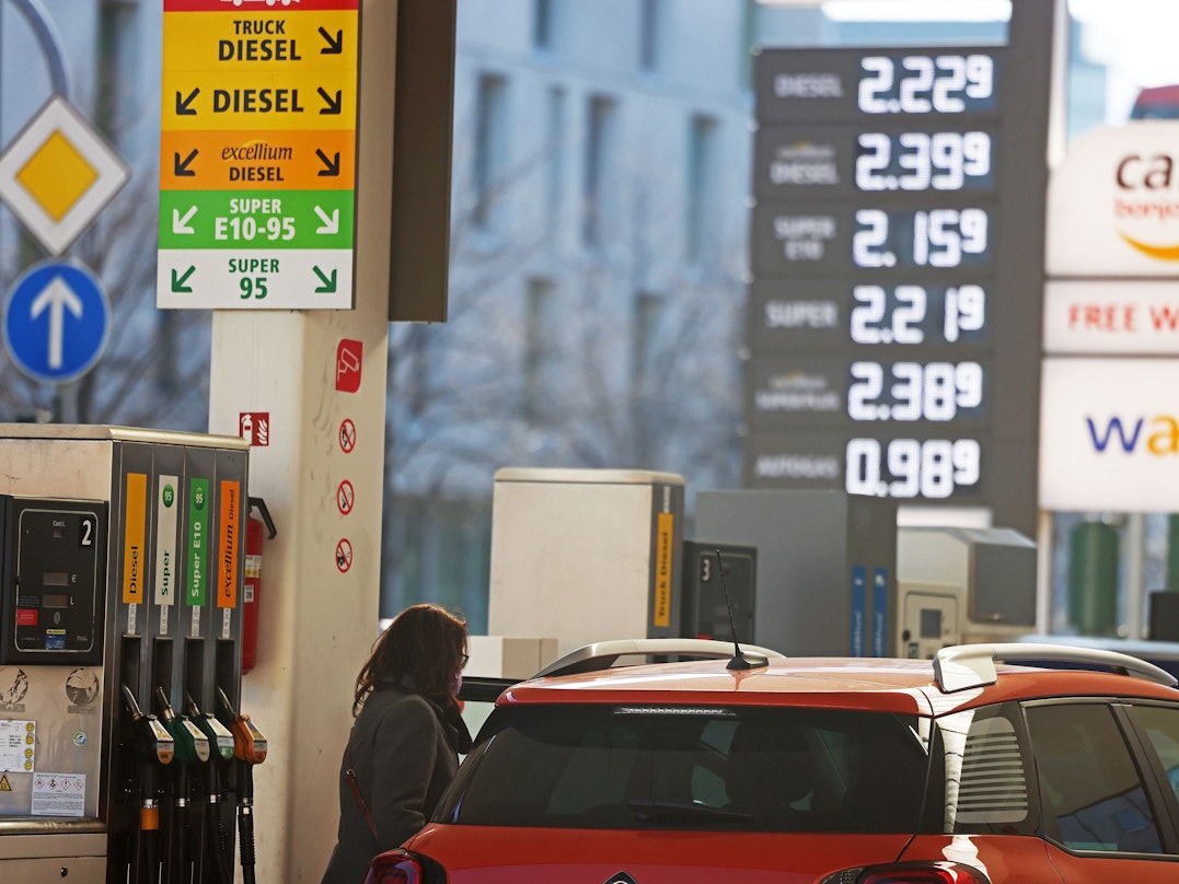 Frau steht mit Auto an einer Tankstelle.