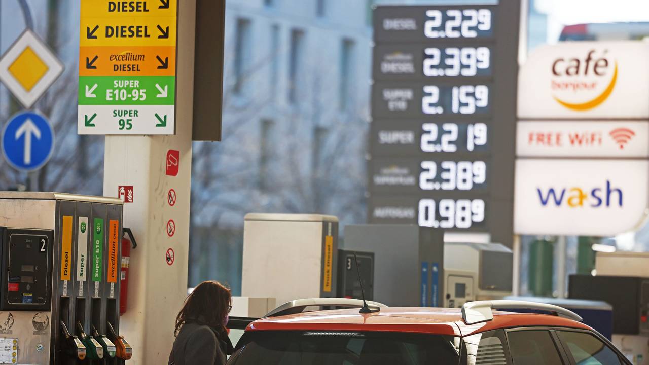 Frau steht mit Auto an einer Tankstelle.