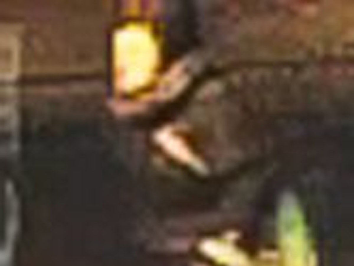 Ein Mann mit Umhängetasche geht an einem Haus entlang.