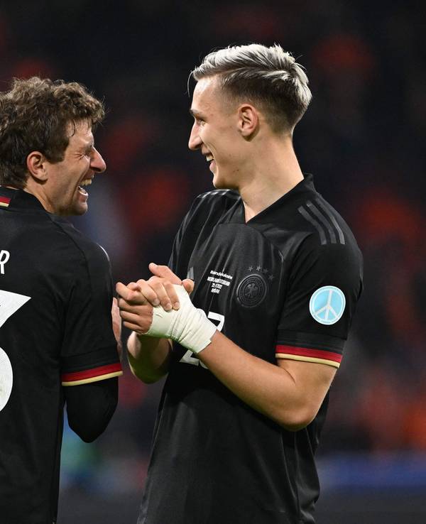 Thomas Müller und Nico Schlotterbeck lachen zusammen auf dem Platz.