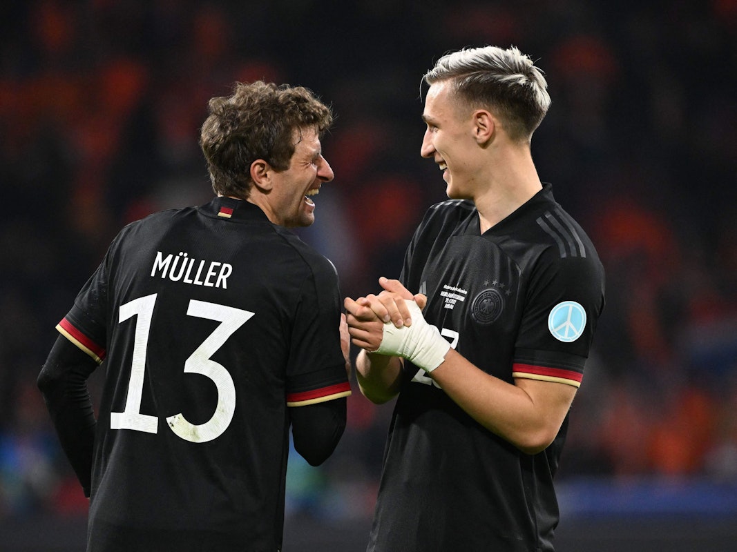 Thomas Müller und Nico Schlotterbeck lachen zusammen auf dem Platz.