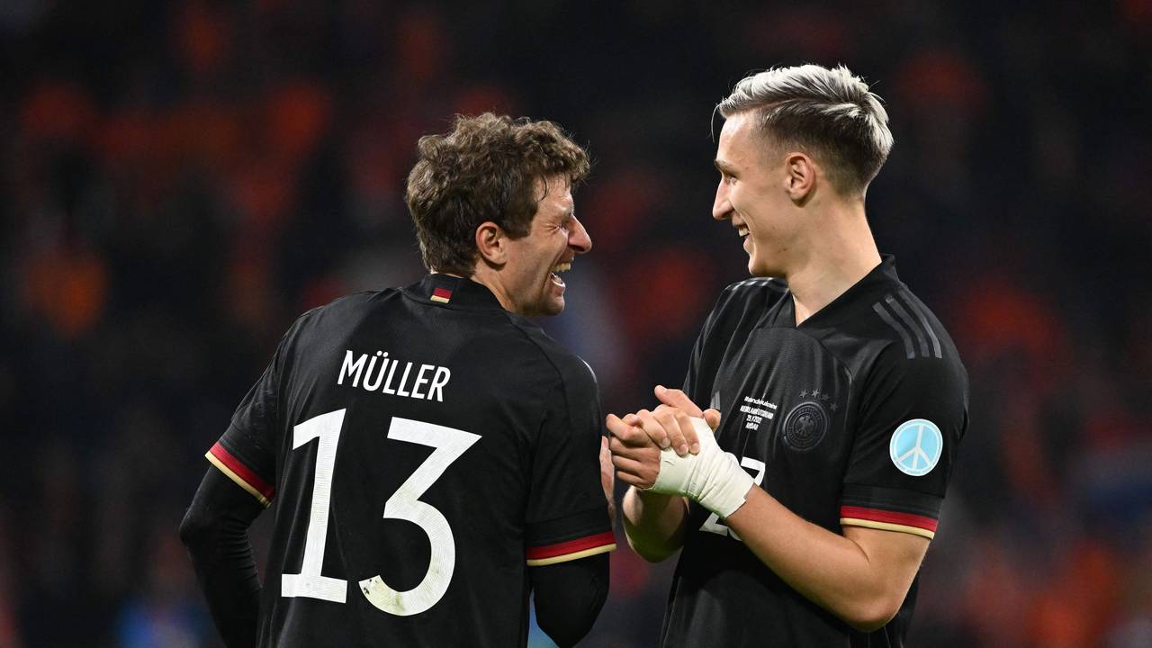 Thomas Müller und Nico Schlotterbeck lachen zusammen auf dem Platz.