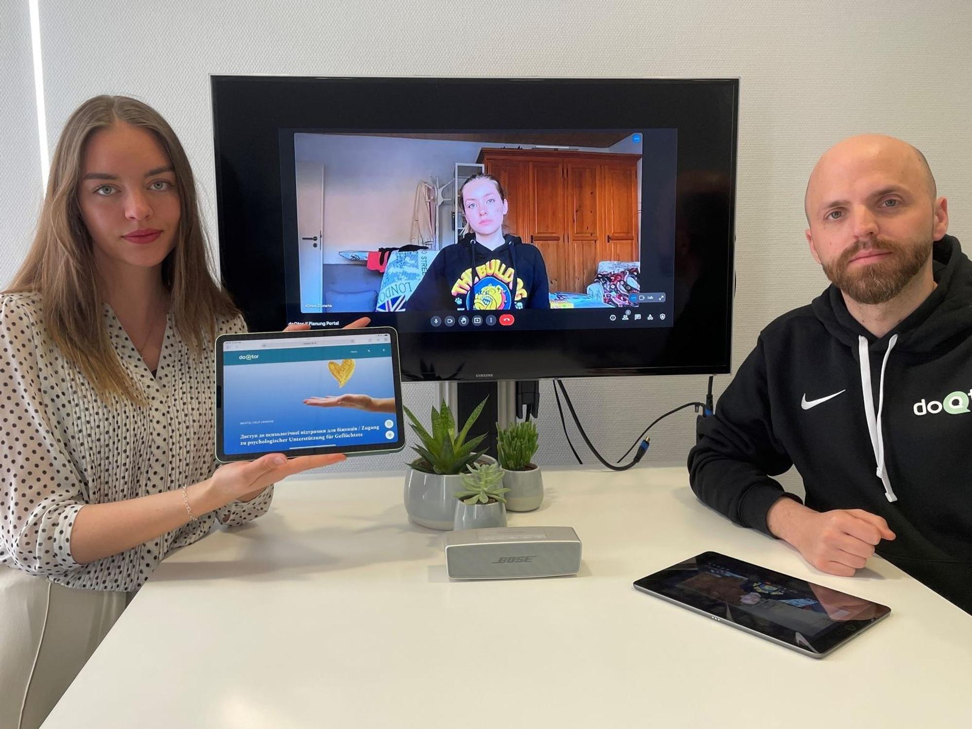 doQtor-Gründer Benjamin Schwarz und seine Mitarbeiterin Emily Herter zusammen mit Yuliia Duliepa auf dem Bildschirm.