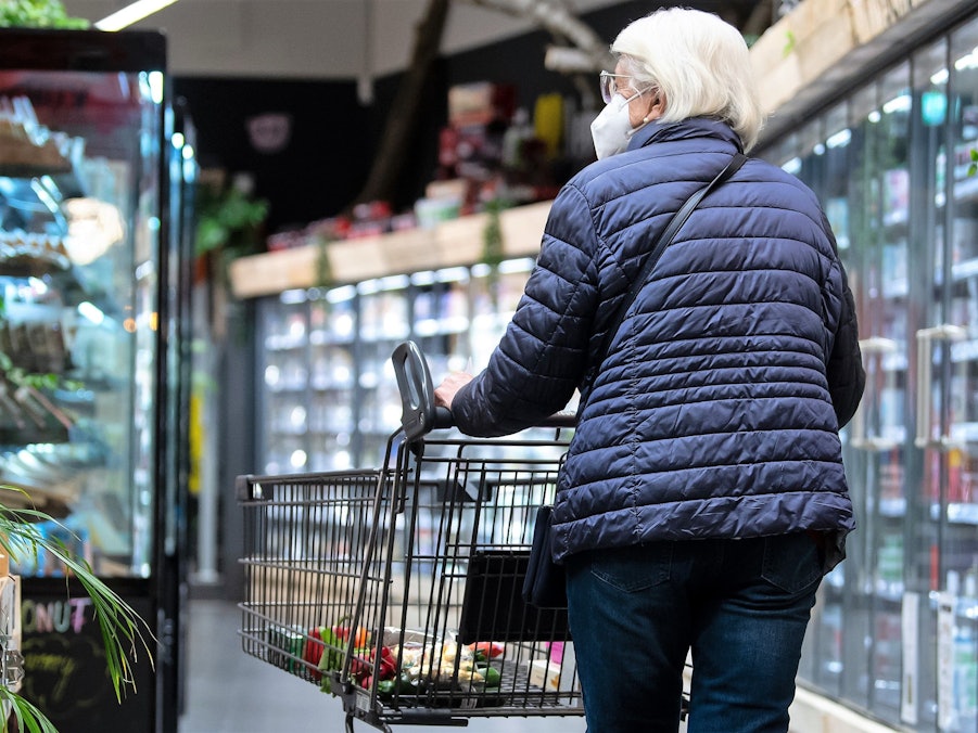 Eine Frau geht Ende März mit ihrem Einkaufswagen durch einen Supermarkt – noch mit einer Maske. Ab April entfällt die Maskenpflicht auch in Supermärkten und Discountern.