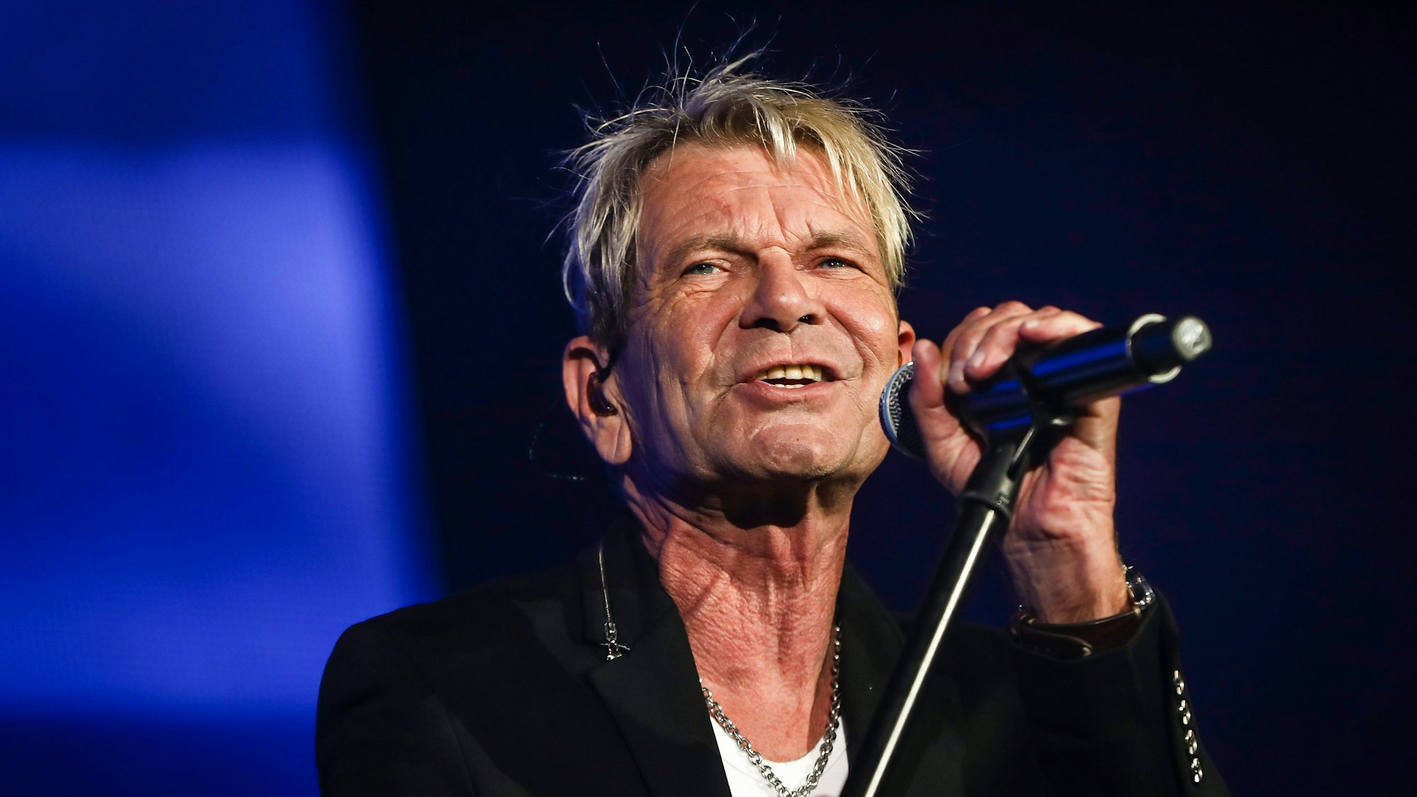 Das undatierte Symbolfoto zeigt den Schlagersänger Matthias Reim in schwarzem Sakko und mit einem Mikrofon in der Hand.