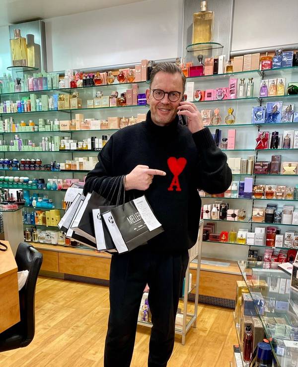 Heinz-Josef Meller steht mit Telefon und Einkaufstüten in seiner Parfümerie Meller in Köln.