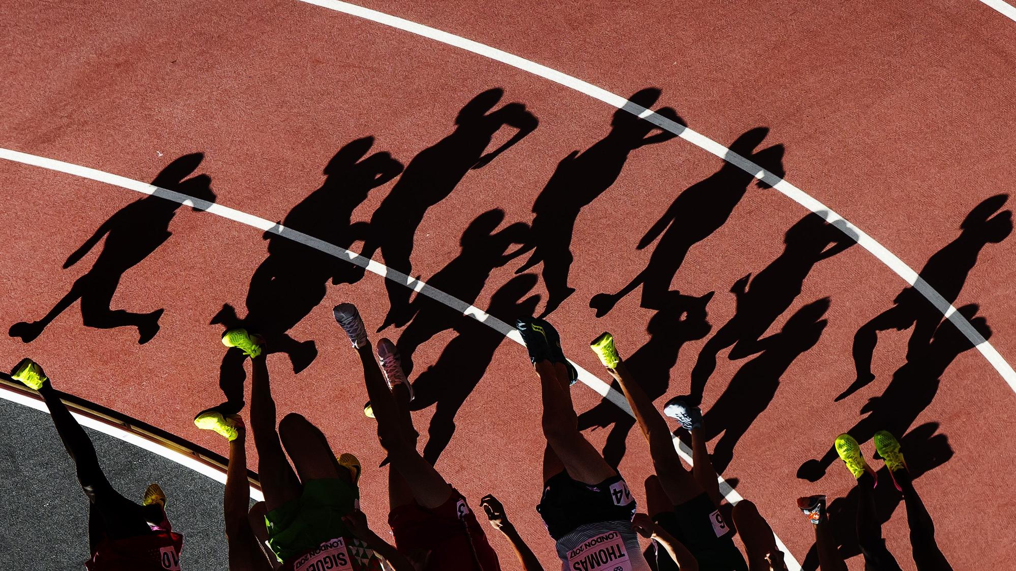 Die Schatten von Läufern sind in einer Kurve auf der Laufbahn zu sehen.