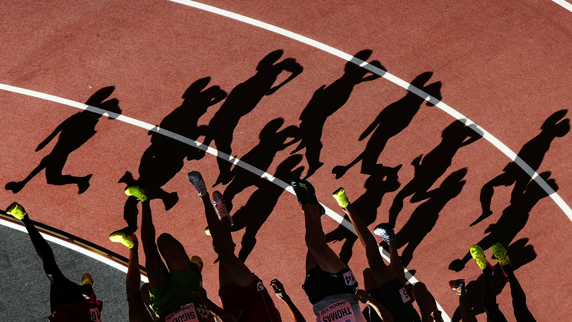 Die Schatten von Läufern sind in einer Kurve auf der Laufbahn zu sehen.
