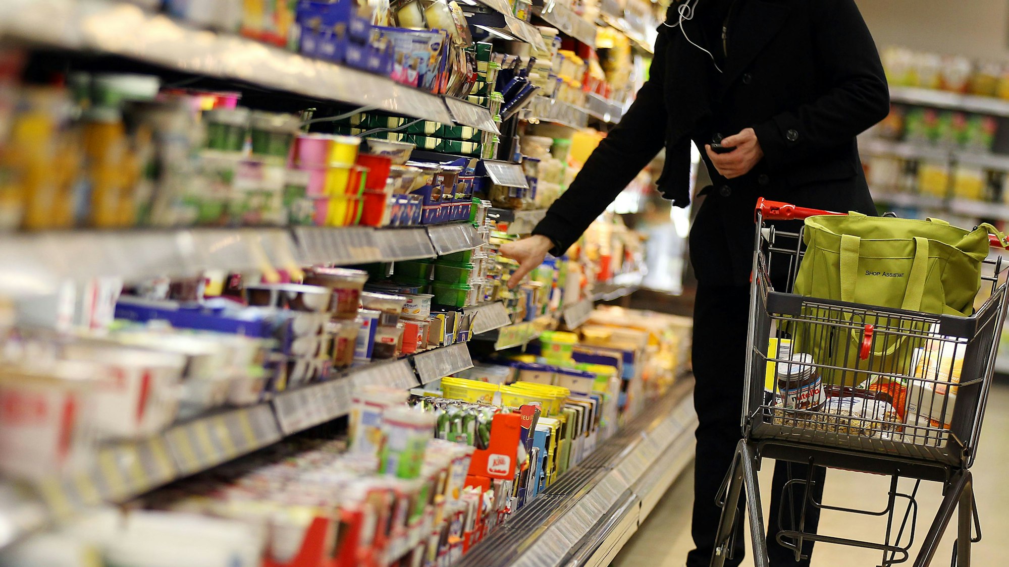 ARCHIV - Ein Kunde steht am 13.02.2012 in Köln in einem Supermarkt am Kühlregal. Die Deutschen greifen im Supermarkt immer häufiger zu Eigenmarken von Edeka, Rewe, Aldi und Co. statt zu den klassischen Markenartikeln. Foto: Oliver Berg/dpa (zu dpa vom 23.01.2015) +++ dpa-Bildfunk +++