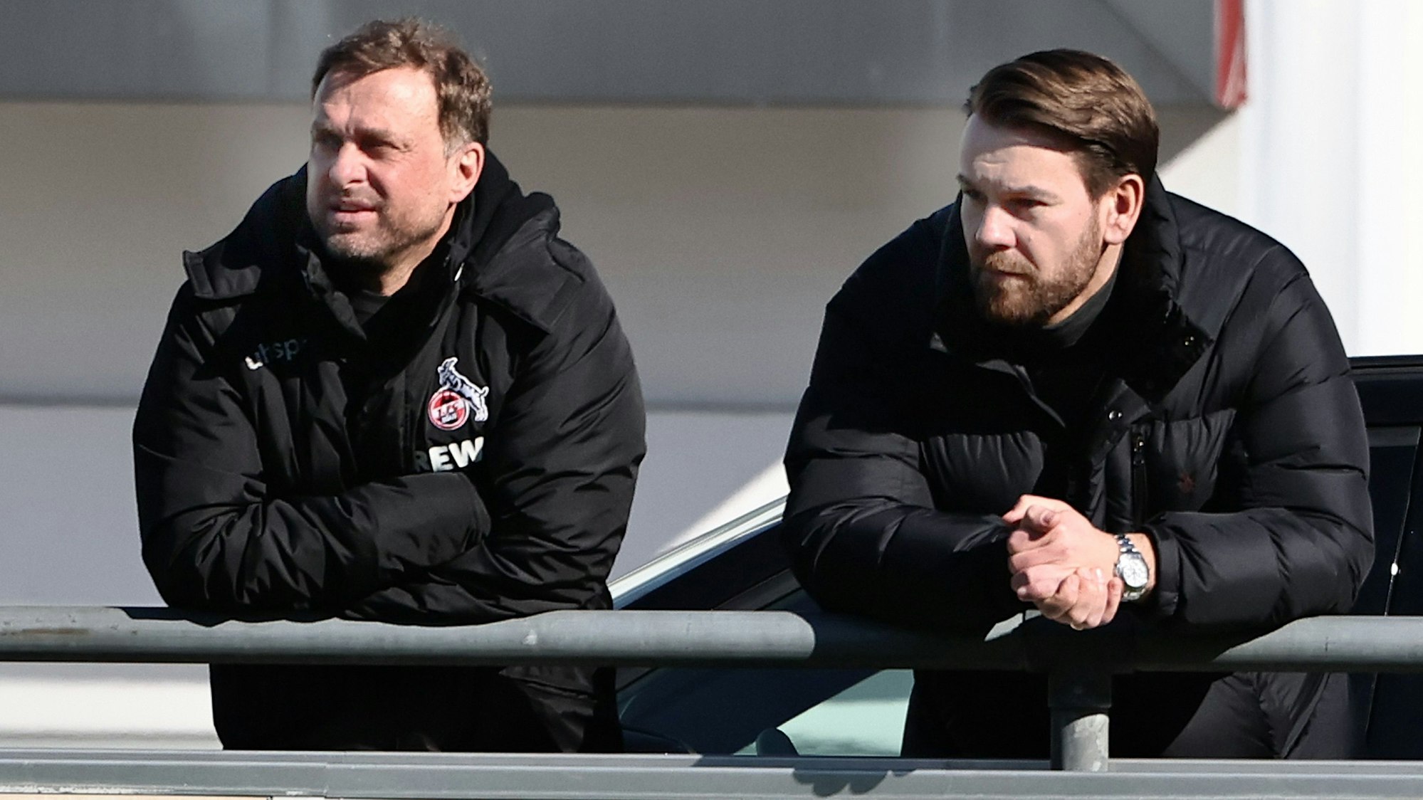 Jörg Jakobs und Thomas Kessler schauen sich gemeinsam eine Trainingseinheit des 1. FC Köln an.