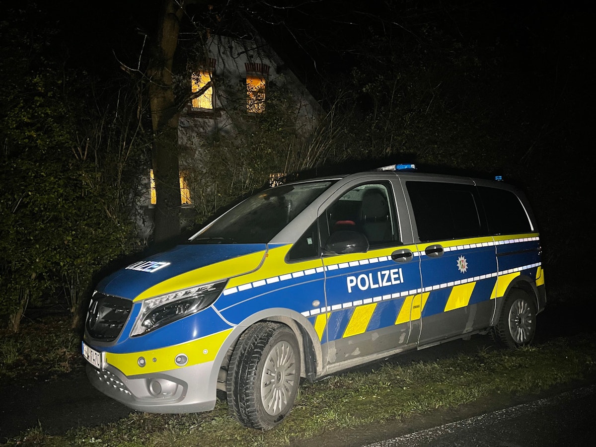 Ein Polizeiauto steht im Dunkeln vor einem Haus.