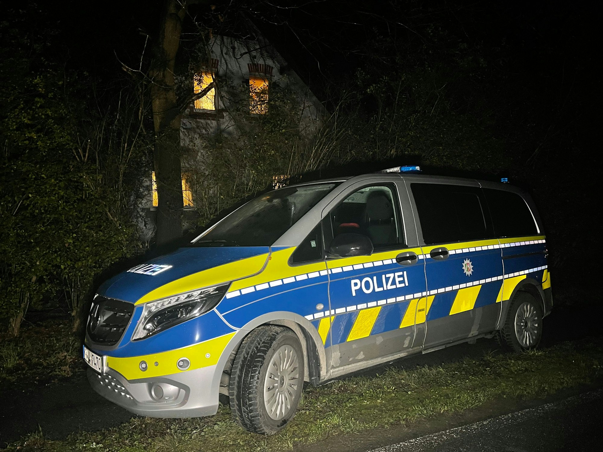 Ein Polizeiauto steht im Dunkeln vor einem Haus.