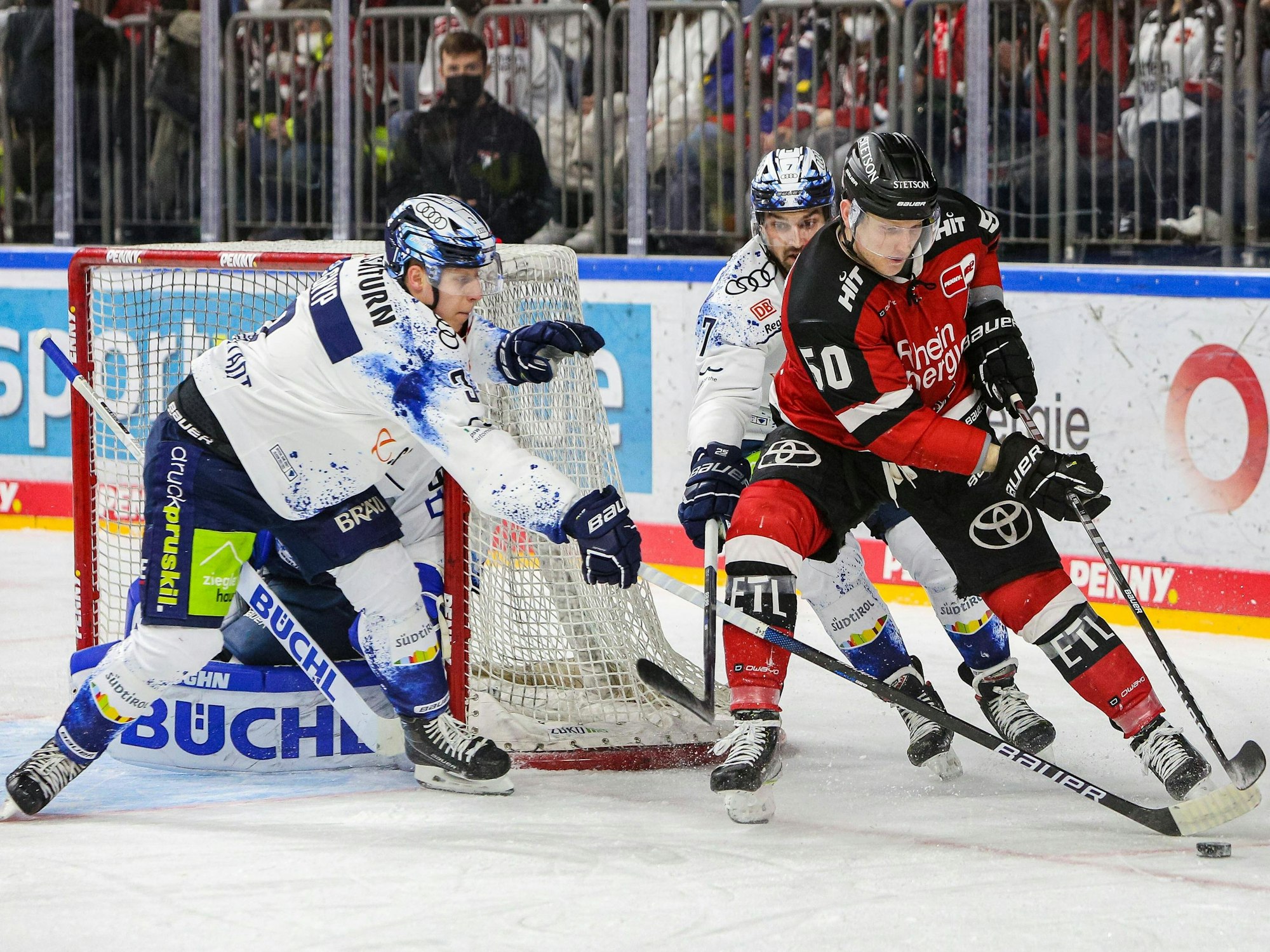 Simon Gnyp (Ingolstadt, links) und Kollege Colton Jobke im Duell um den Puck mit Alexander Oblinger (Kölner Haie).