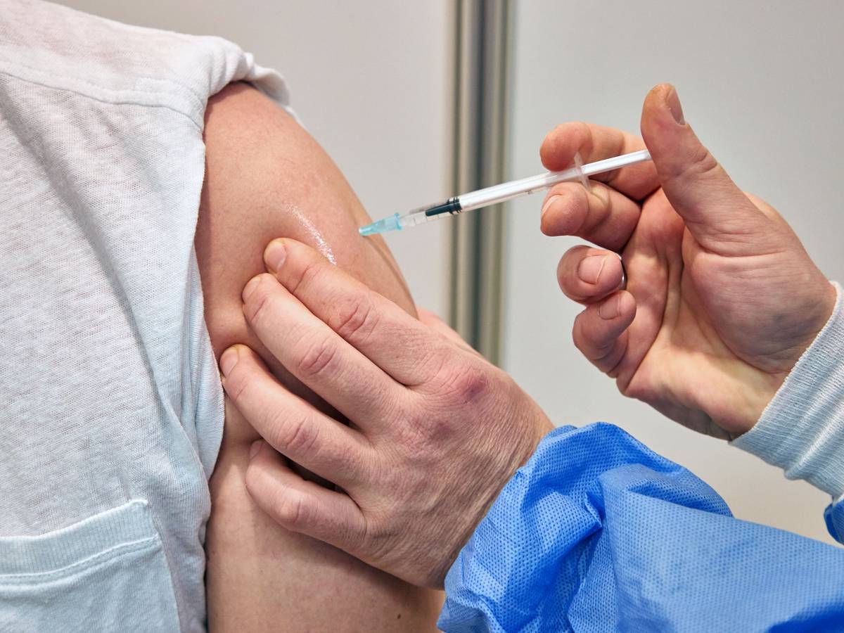 Ein Gesundheits-und Krankenpfleger verimpft in einem Impfzentrum einem Mann den Impfstoff Nuvaxovid des Pharmaunternehmens Novavax. Seit heute werden auch Corona-Impfungen mit dem neuen Impfstoff von Novavax angeboten.
