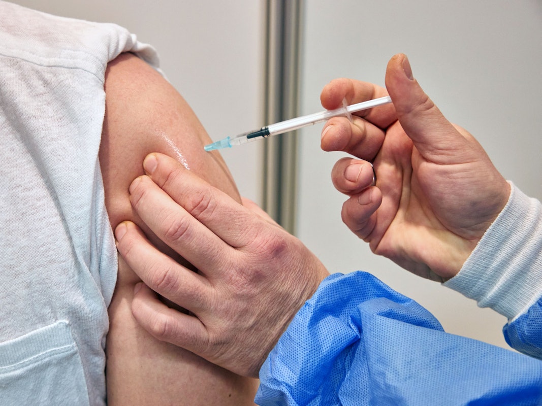 Ein Gesundheits-und Krankenpfleger verimpft in einem Impfzentrum einem Mann den Impfstoff Nuvaxovid des Pharmaunternehmens Novavax. Seit heute werden auch Corona-Impfungen mit dem neuen Impfstoff von Novavax angeboten.