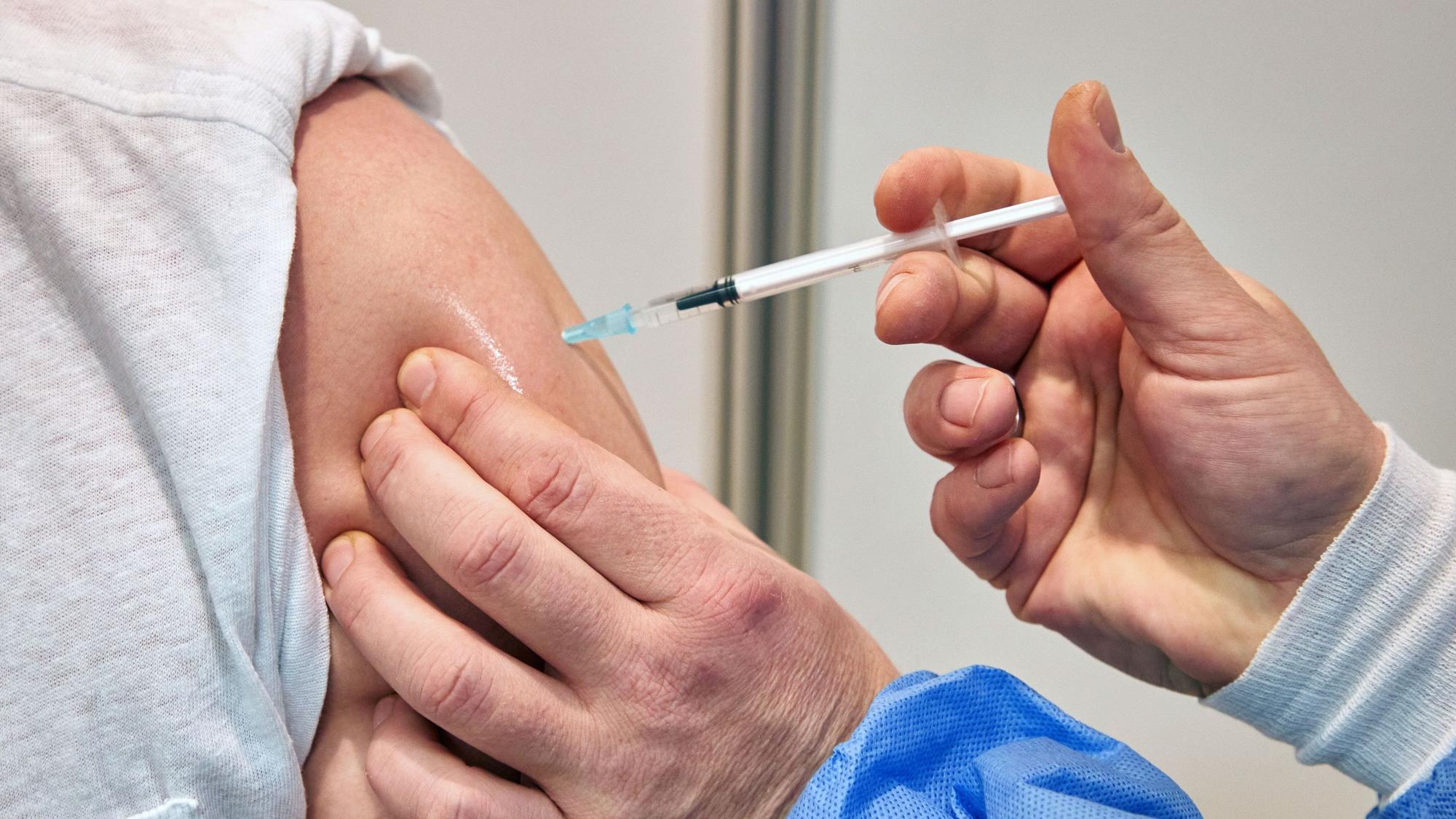 Ein Gesundheits-und Krankenpfleger verimpft in einem Impfzentrum einem Mann den Impfstoff Nuvaxovid des Pharmaunternehmens Novavax.