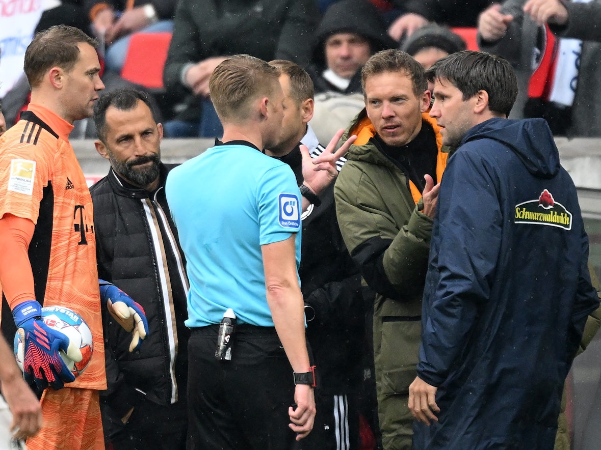 Schiedsrichter Christian Dingert (M.) spricht mit Bayern-Trainer Julian Nagelsmann (2.v.r.) und Freiburgs Co-Trainer Florian Bruns (r.) über den Wechselfehler der Münchner im Spiel beim SC Freiburg.