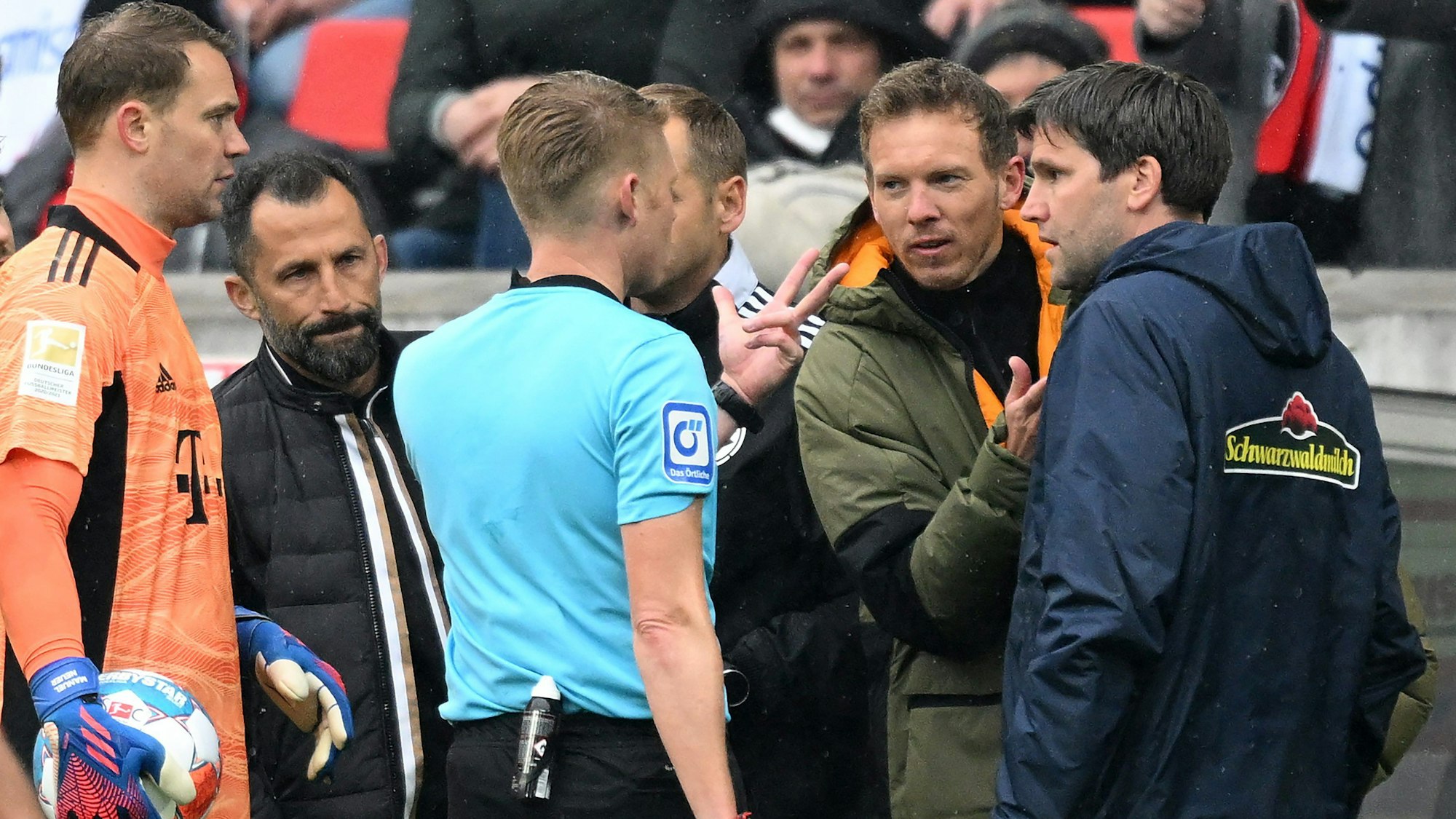 Schiedsrichter Christian Dingert (M.) spricht mit Bayern-Trainer Julian Nagelsmann (2.v.r.) und Freiburgs Co-Trainer Florian Bruns (r.) über den Wechselfehler der Münchner im Spiel beim SC Freiburg.