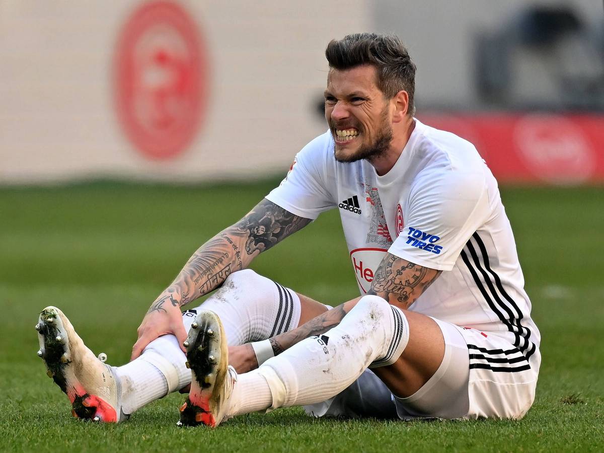 Daniel Ginczek (Düsseldorf) sitzt auf dem Rasen.