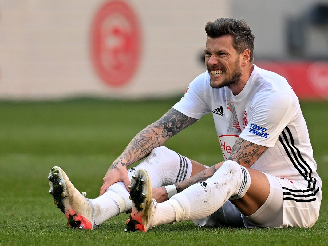 Daniel Ginczek (Düsseldorf) sitzt auf dem Rasen.