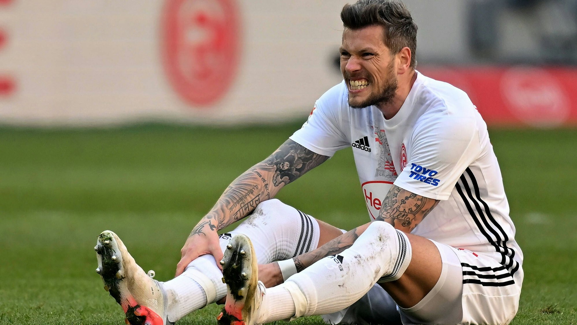 Daniel Ginczek (Düsseldorf) sitzt auf dem Rasen.