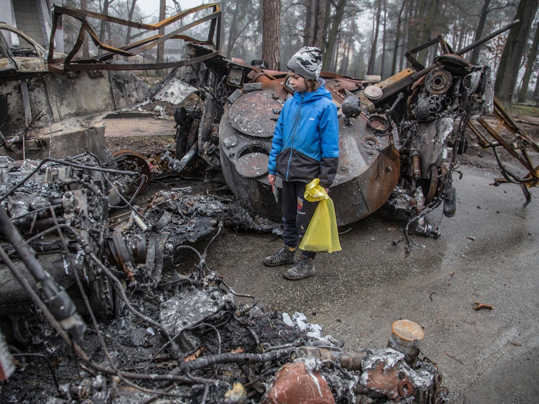 Ein Junge betrachtet einen zerstörten russischen Panzer nach den jüngsten Kämpfen in Butscha am 1. April 2022, in der Nähe von Kyjiw. Aus der von ukrainischen Truppen zurückeroberten Stadt werden grauenhafte Verbrechen gemeldet.