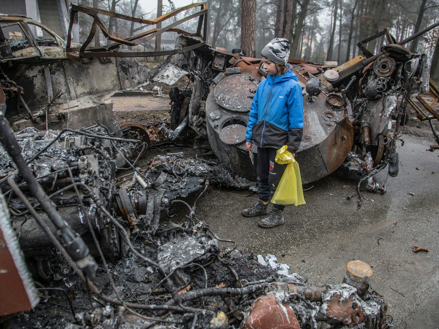 Ein Junge betrachtet einen zerstörten russischen Panzer nach den jüngsten Kämpfen in Butscha am 1. April 2022, in der Nähe von Kyjiw. Aus der von ukrainischen Truppen zurückeroberten Stadt werden grauenhafte Verbrechen gemeldet.