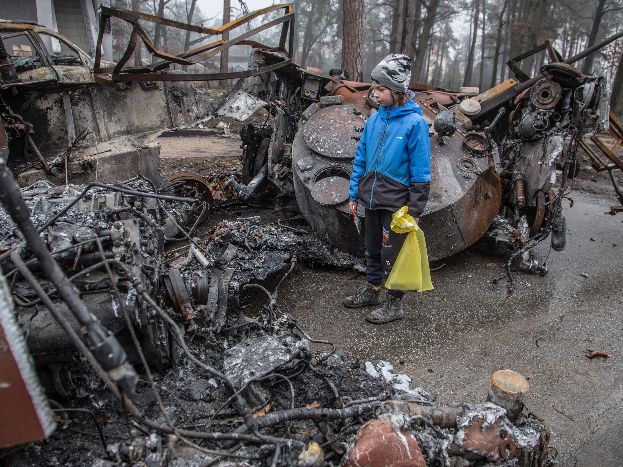 Ein Junge betrachtet einen zerstörten russischen Panzer nach den jüngsten Kämpfen in Butscha am 1. April 2022, in der Nähe von Kyjiw. Aus der von ukrainischen Truppen zurückeroberten Stadt werden grauenhafte Verbrechen gemeldet.