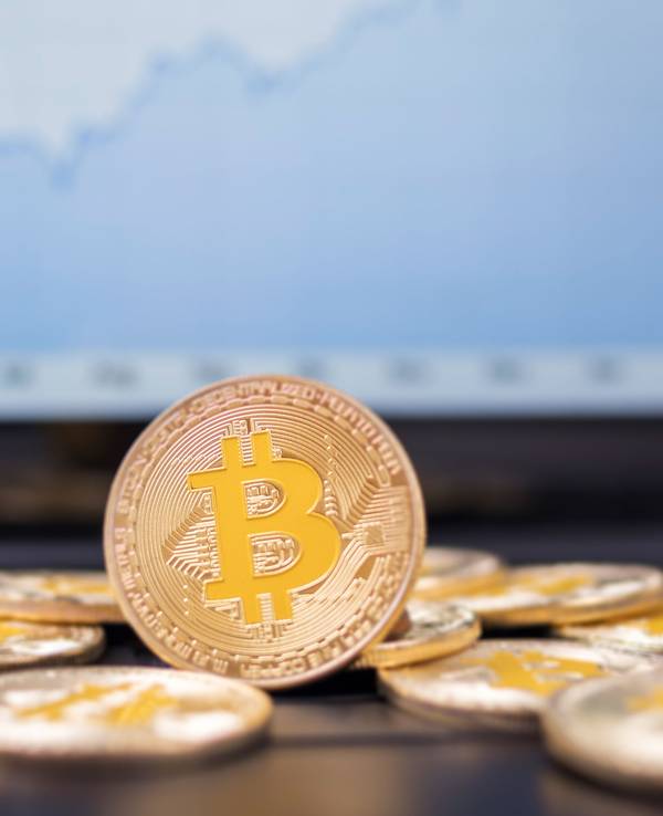 Münzen mit dem Bitcoin-Logo liegen auf der Tastatur eines Laptops.