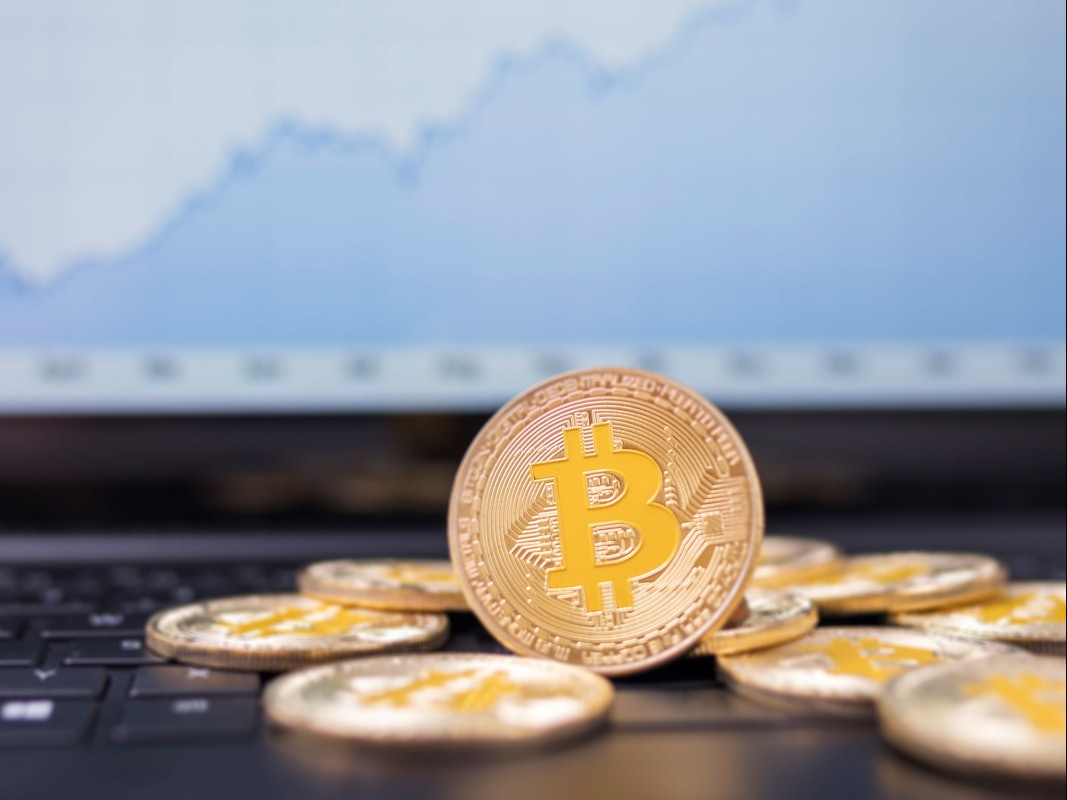 Münzen mit dem Bitcoin-Logo liegen auf der Tastatur eines Laptops.