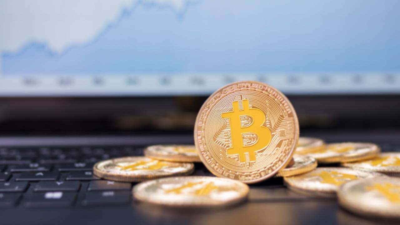 Münzen mit dem Bitcoin-Logo liegen auf der Tastatur eines Laptops.
