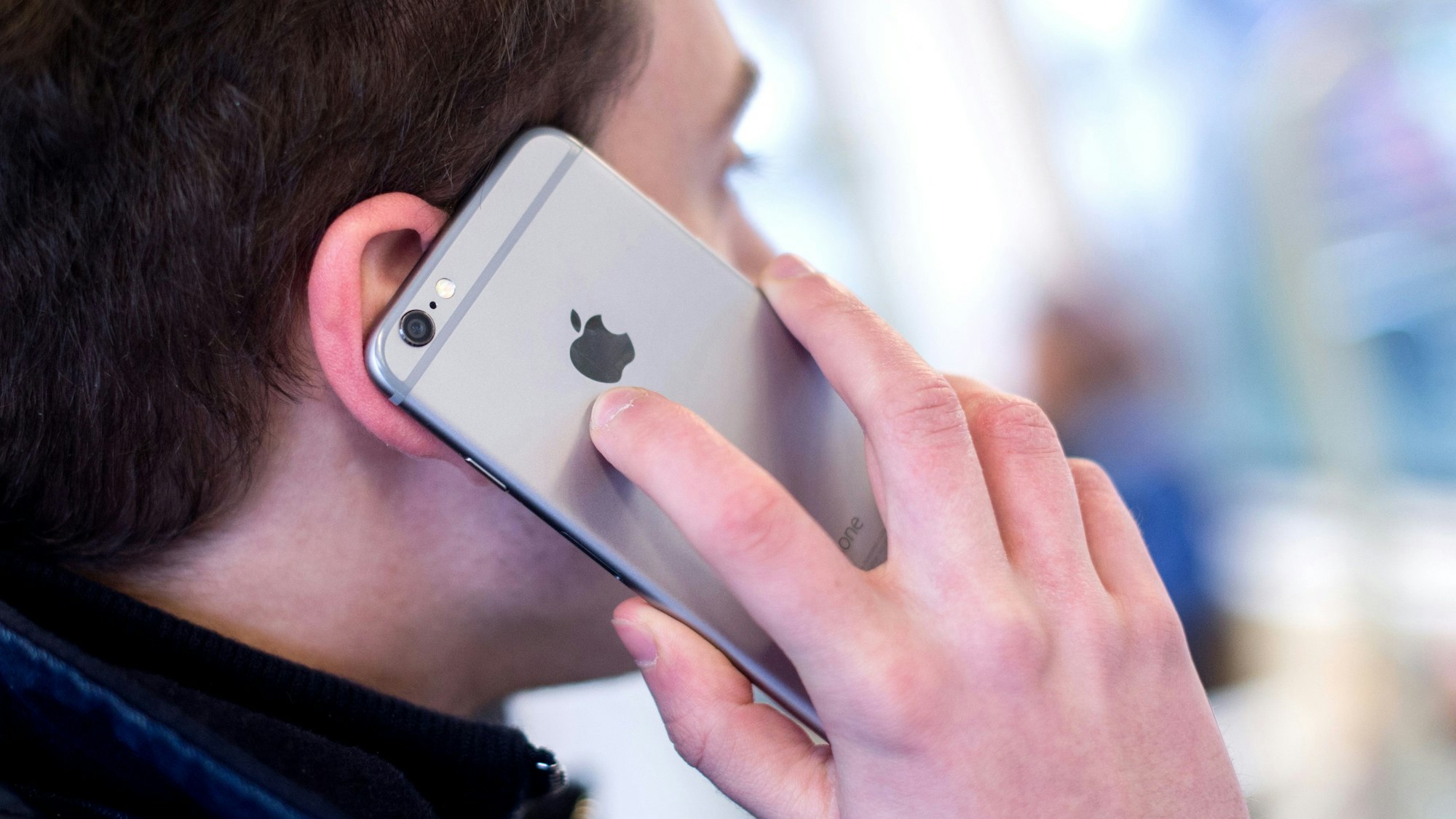 Ein junger Mann steht in einer Stadtbahn und telefoniert dabei mit seinem Smartphone.