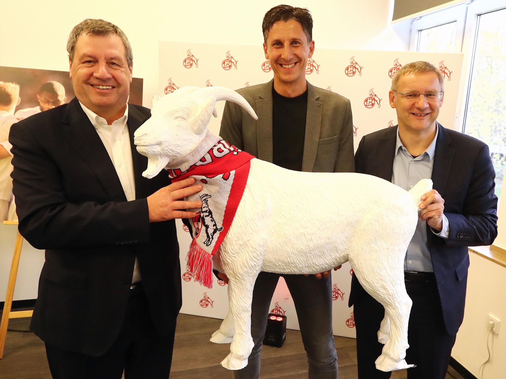 Christian Keller hält beim 1. FC Köln mit Werner Wolf und Eckhard Sauren einen Geißbock.