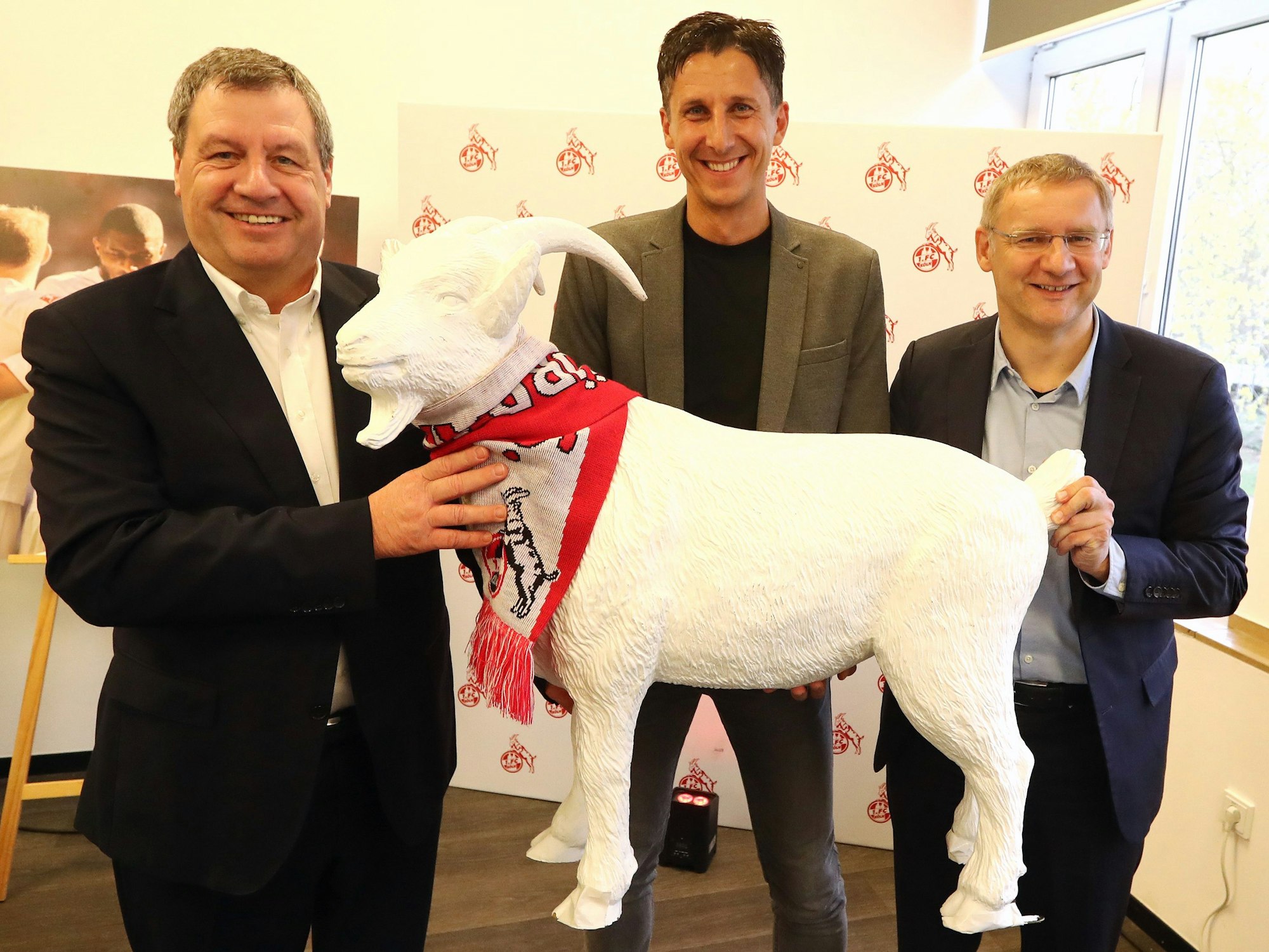 Christian Keller hält beim 1. FC Köln mit Werner Wolf und Eckhard Sauren einen Geißbock.