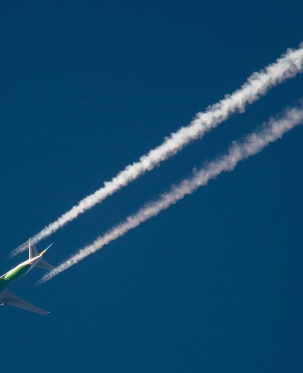 Ein Flugzeug hinterlässt am Himmel Kondensstreifen.