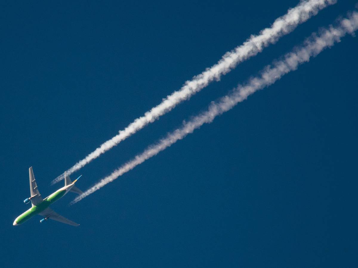 Ein Flugzeug hinterlässt am Himmel Kondensstreifen.