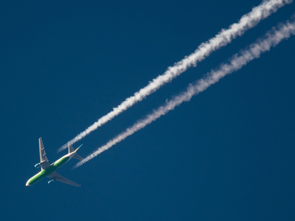Ein Flugzeug hinterlässt am Himmel Kondensstreifen.
