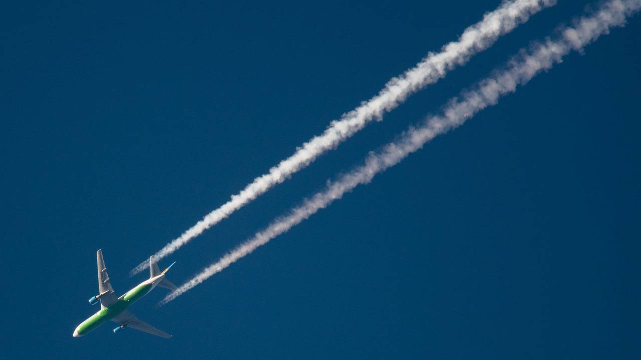 Ein Flugzeug hinterlässt am Himmel Kondensstreifen.