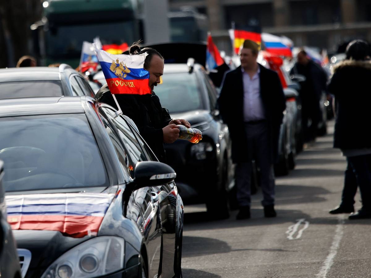 Flaggen mit den russischen Nationalfarben und dem russischen Staatswappen wehen an einem Auto auf dem Olympiaplatz vor dem Olympiastadion. Etwa 900 Menschen haben am Sonntag in Berlin an einem Autokorso mit russischen Fahnen teilgenommen.