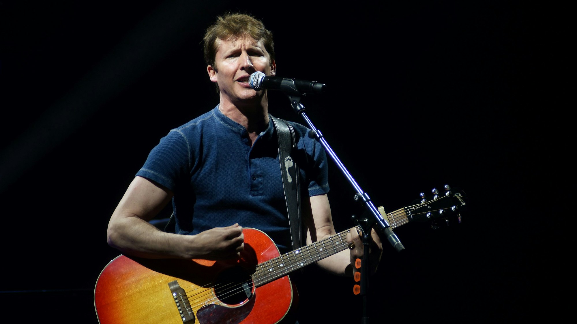 Emotionaler James Blunt singt mit seiner Gitarre in der Lanxess Arena in Köln.