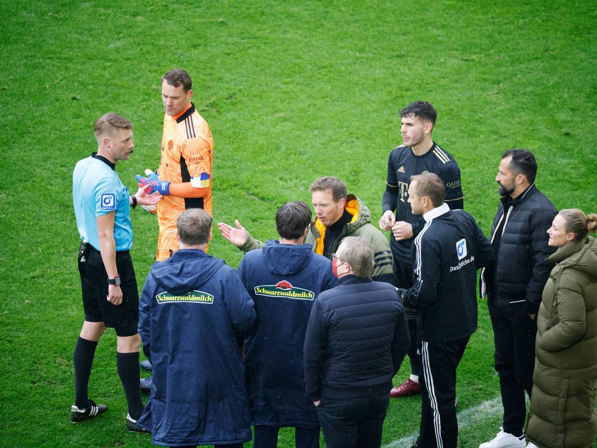 Schiedsrichter Christian Dingert (l in blau) bespricht mit dem vierten Offiziellen sowie Spielern und Verantwortlichen des FC Bayern München sowie des SC Freiburg das Vorgehen.