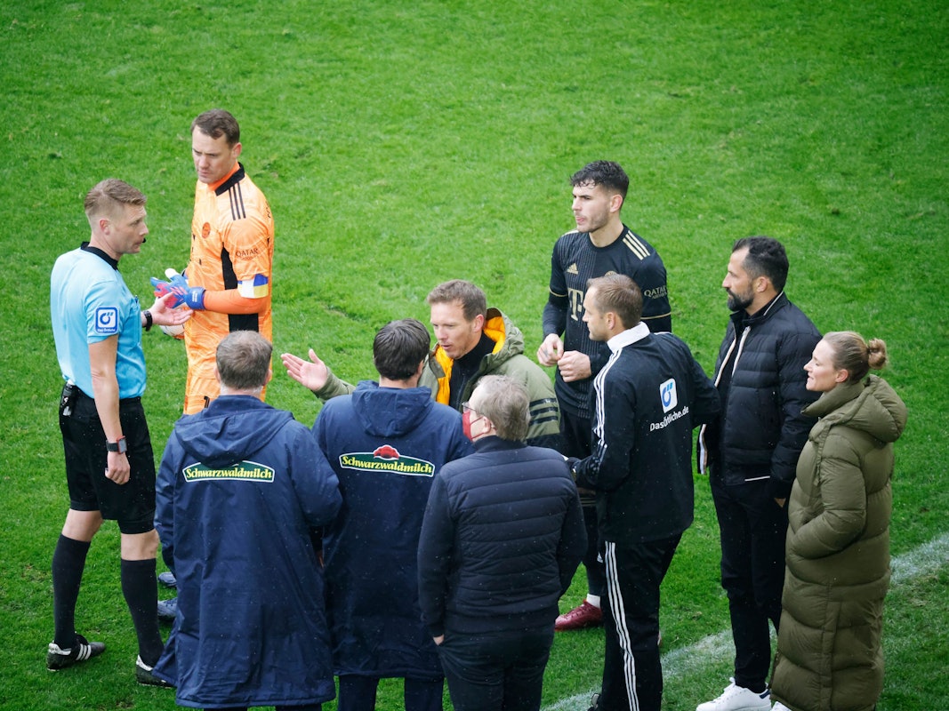 Schiedsrichter Christian Dingert (l in blau) bespricht mit dem vierten Offiziellen sowie Spielern und Verantwortlichen des FC Bayern München sowie des SC Freiburg das Vorgehen.