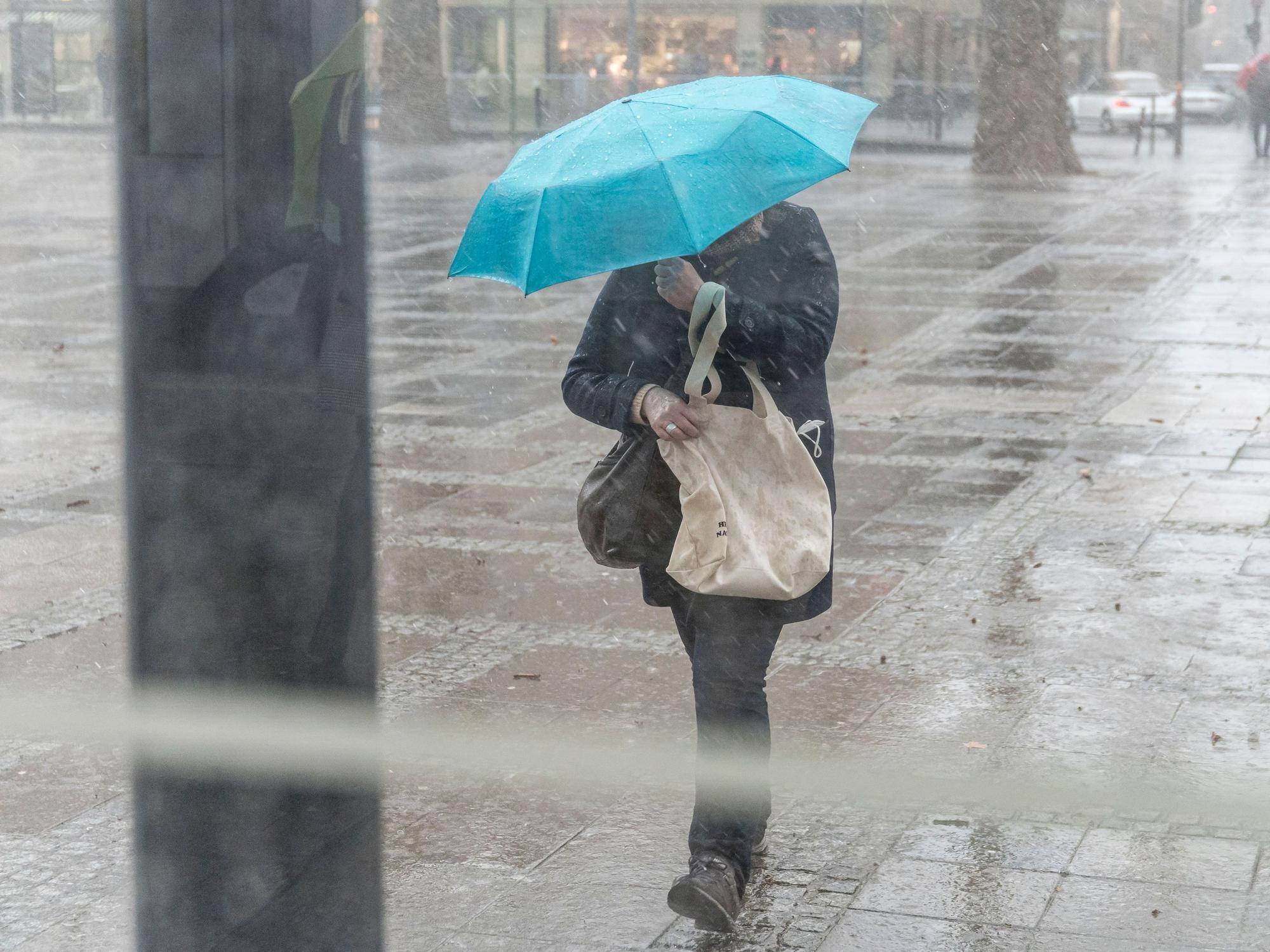 Eine Person läuft durch den Regen und verdeckt das Gesicht mit einem Regenschirm. In Köln fällt noch die restliche Woche starker Regen.